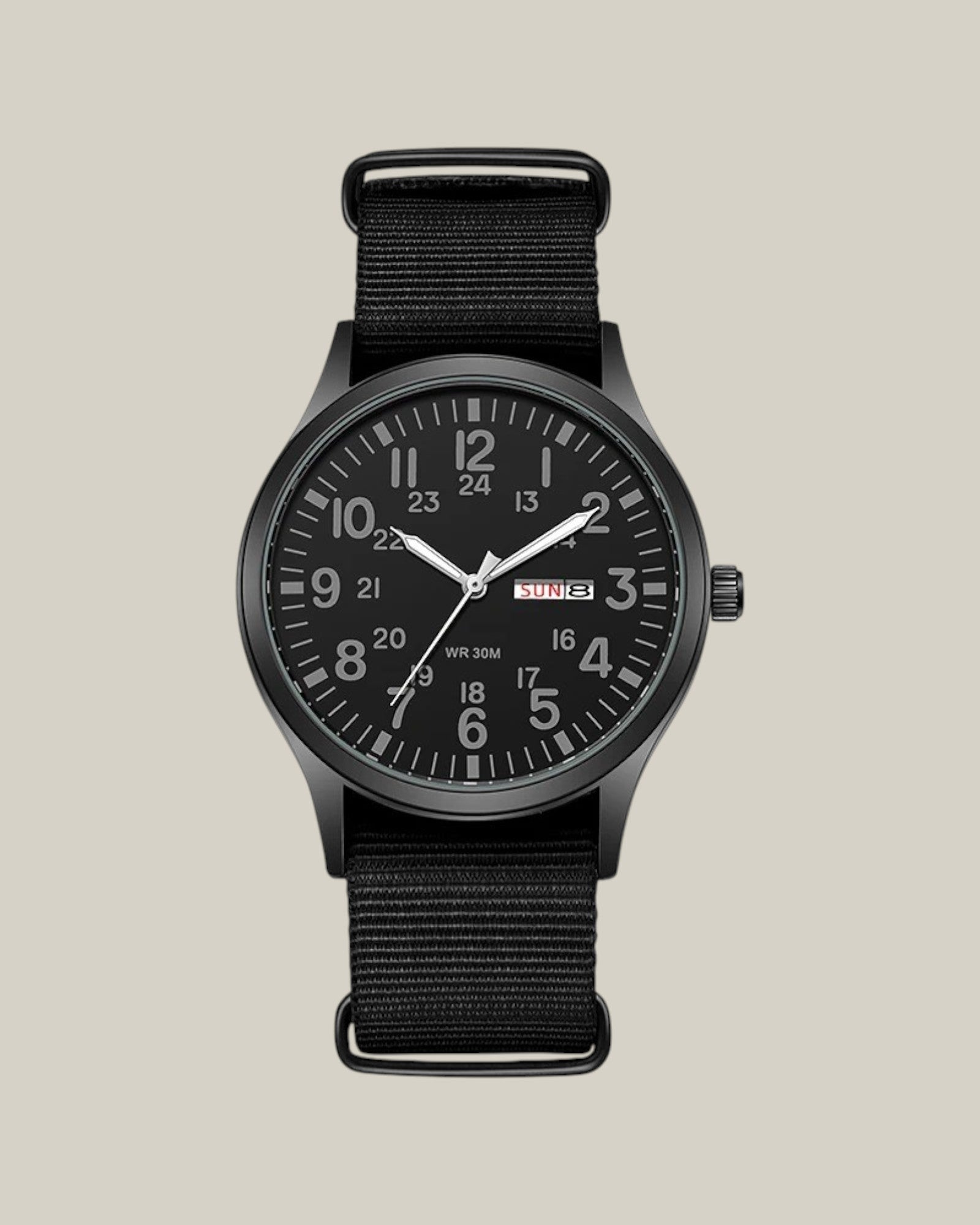Relógio masculino com pulseira de nylon preto e mostrador preto da marca Bravio. O relógio tem calenário e ponteiros luminosos no escuro.